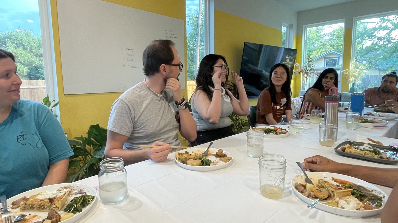Members seated around a table during a Family Origin workshop, sharing a meal together.