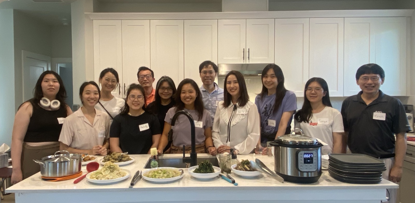 A large group gathered around a kitchen island full of shared dishes during Taiwan Night.
